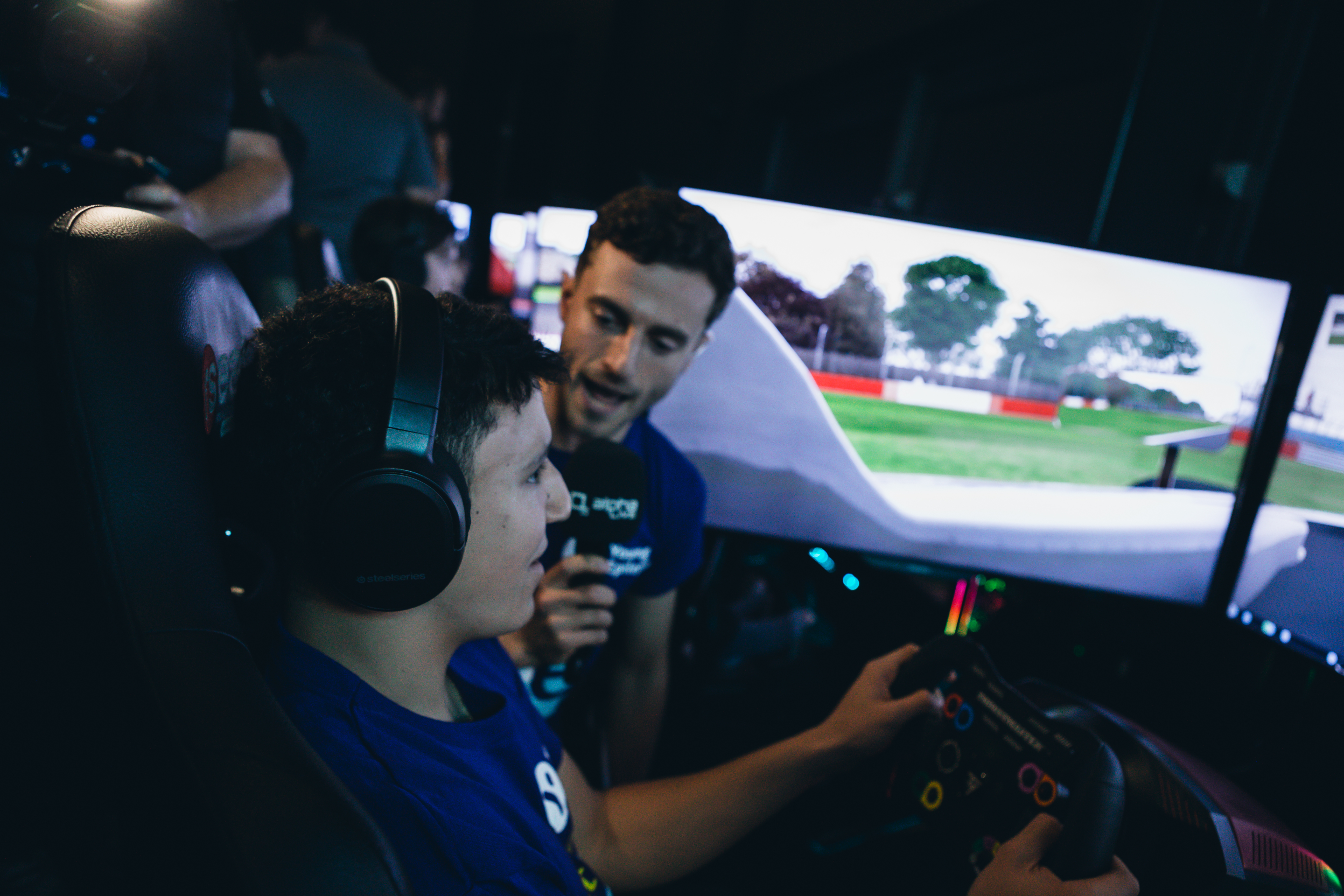 A competitor at the wheel of a racing simulator with triple screens.